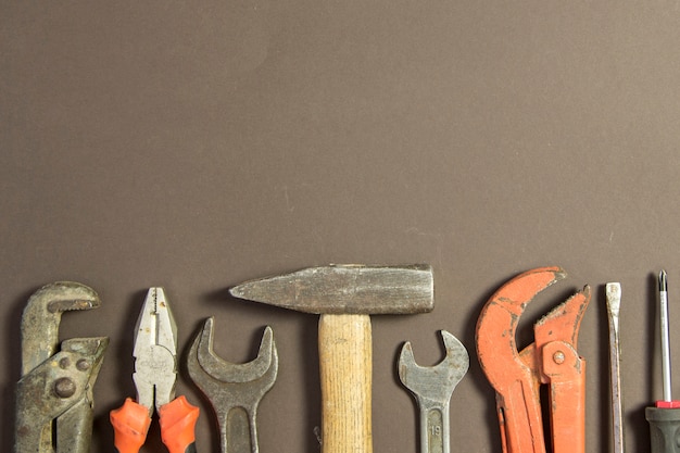 Free photo construction tools on textured grunge paper consisting of pipe wrench, screwdriver, metal, hammer and free copy space on the top