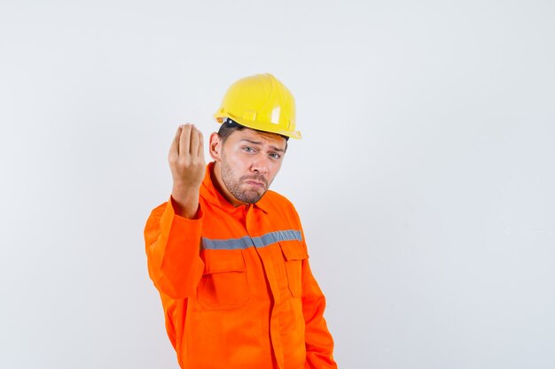 Construction worker doing italian gesture, being displeased with dumb question in uniform, helmet , front view.