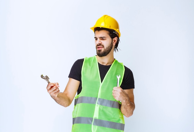 Construction worker holding wrench and spanner for mechanical repair.