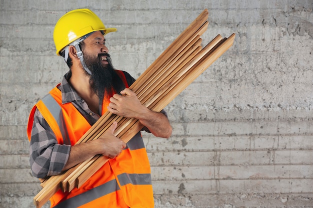 Free photo construction worker is carrying wood planks very hard on construction site.