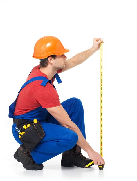 Construction worker measuring the wall on white