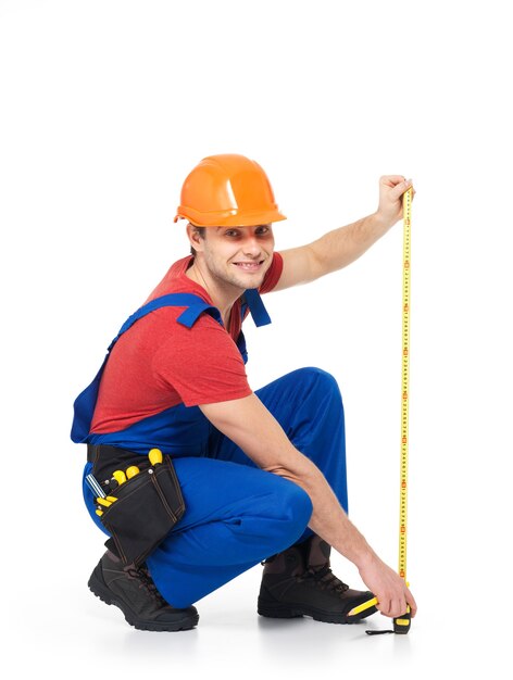 Construction worker measuring the wall on white