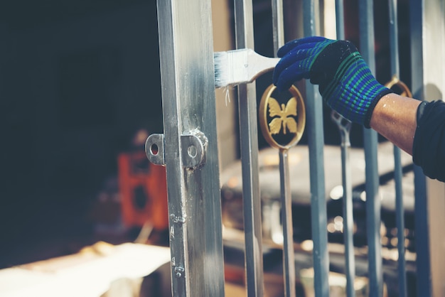 Construction worker painting fence at home