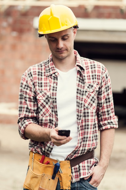 Construction worker texting on mobile phone