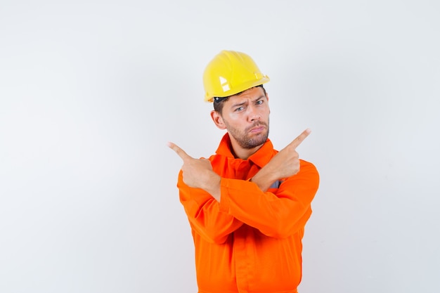 Foto gratuita operaio edile in uniforme, casco rivolto lontano e guardando fiducioso, vista frontale.