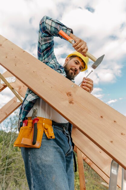 Construction worker with hammer building the roof of the house