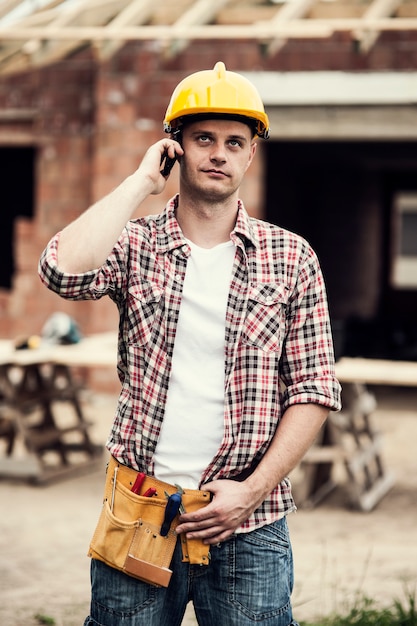 携帯電話を持つ建設労働者