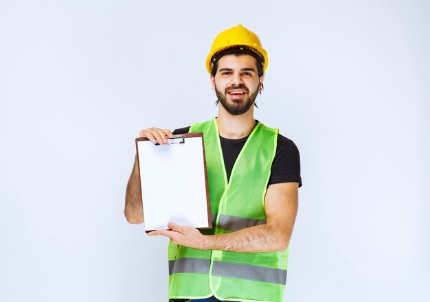 Construction worker with a yellow helmet holding a project report.