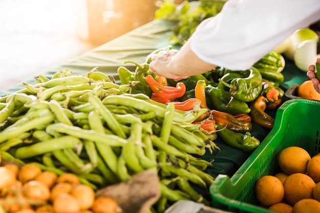 Рука потребителя выбирая свежий овощ на рынке гастронома