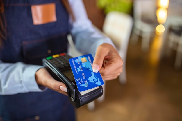 Contactless payment concept female holding credit card near nfc technology on counter client make transaction pay bill on terminal rfid cashier machine in restaurant store close up view