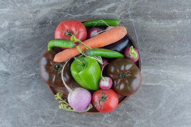 Container full of mixed vegetables , on the marble table. 