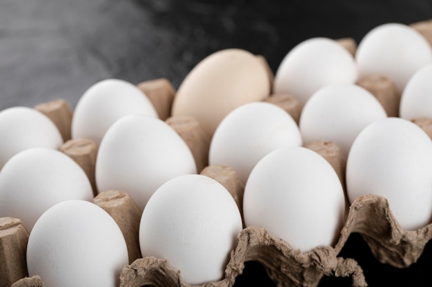 Free photo container of white eggs on black surface.