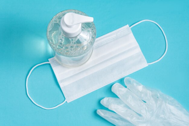 container with alcohol gel, gloves and surgical mask 