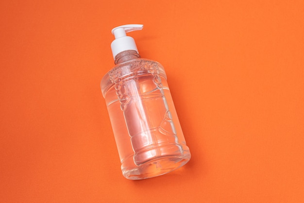 Free photo container with alcohol gel on the orange wall