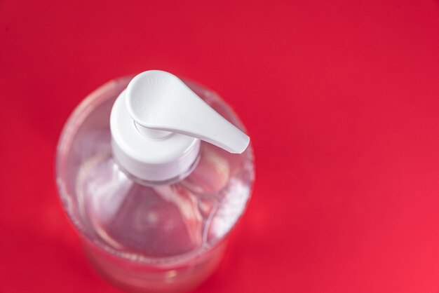 Container with alcohol gel on the red wall