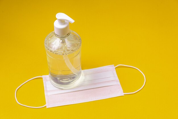 Container with alcohol gel and surgical mask on the orange