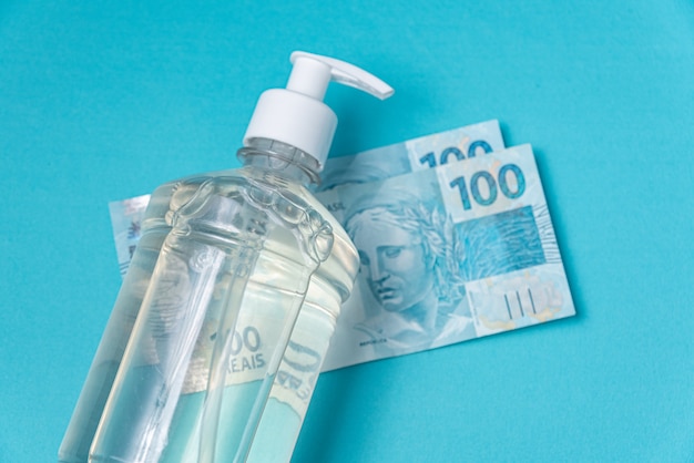 Free photo container with gel alcohol and brazilian real money,