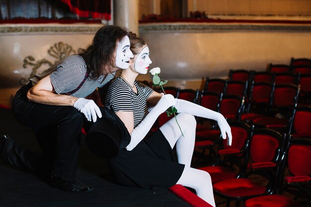 Contemplated couple mime artist sitting on stage in the auditorium