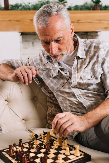 Free photo contemplated elderly man playing chess