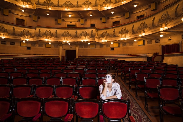 Contemplated female mime sitting on chair