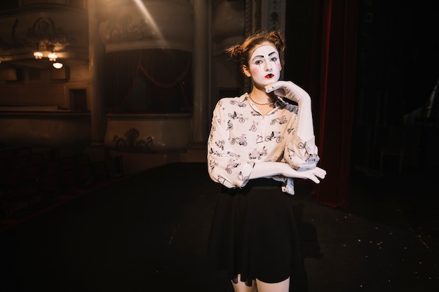 Contemplated female mime standing on stage