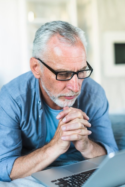 Free photo contemplated senior man looking at laptop