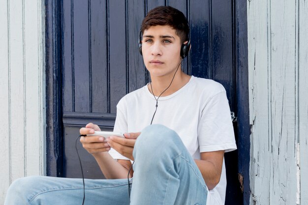 Contemplated young boy listening music on cellphone