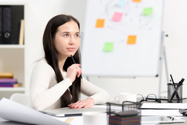 Contemplated young businesswoman at workplace in the office