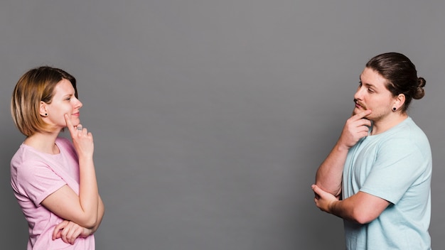 Contemplated young couple standing face to face against grey wall