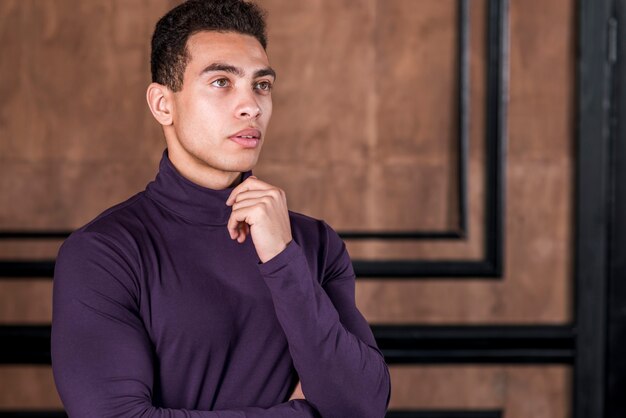 Free photo contemplated young man standing against wall