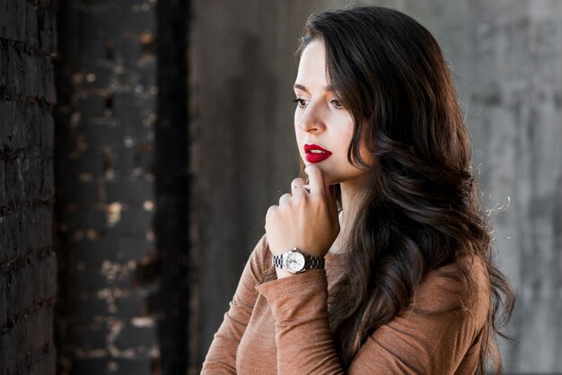 Contemplated young woman with wristwatch on his hand looking away