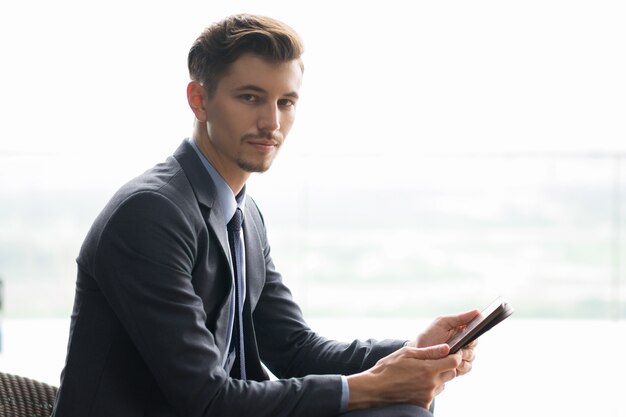 Content Adult Businessman Sitting and Using Tablet