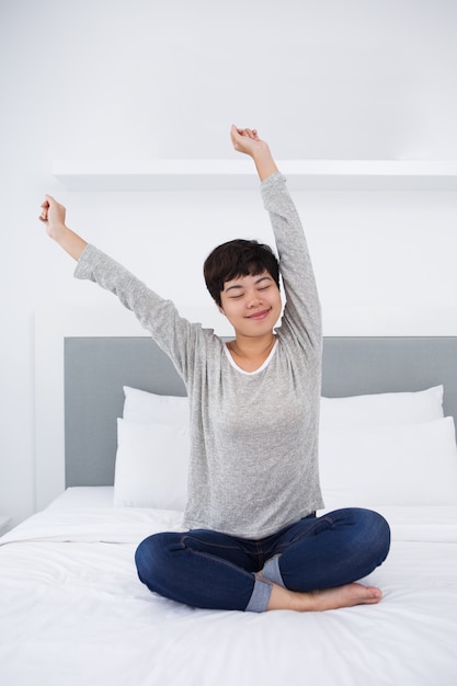 Content Asian Woman Sitting on Bed and Stretching