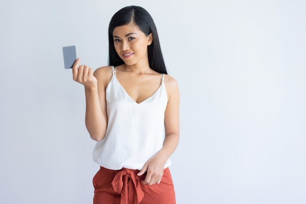 Содержимая азиатская женщина используя кредитную карточку для оплаты