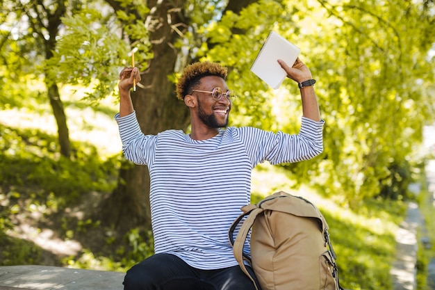 Content black posing with notepad in park