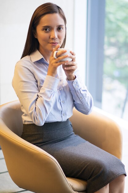 Content Businesswoman Drinking Coffee in Armchair