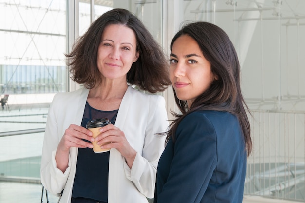 Content colleagues relaxing and looking at camera in office hall