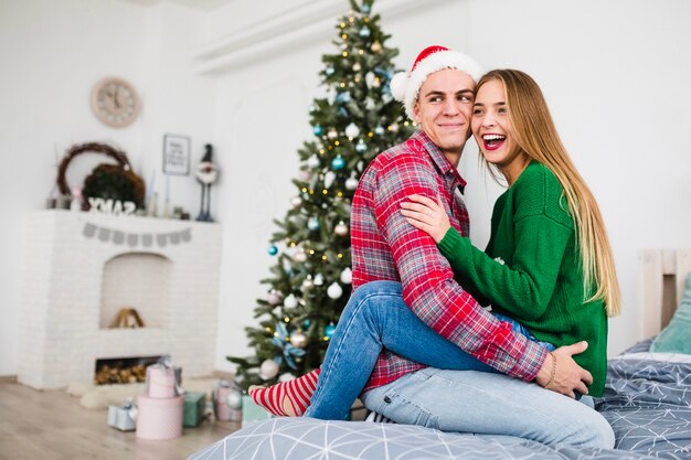 Content couple on bed next to christmas tree