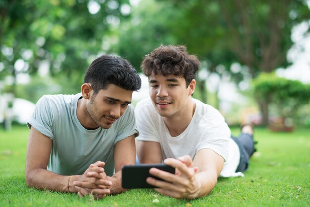 Content couple of men posing for selfie on smartphone