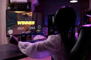 Foto gratuita creatore di contenuti che gioca a un torneo di videogiochi sul computer, celebrando la vittoria. giocatore femminile che vince il campionato di giochi d'azione, divertendosi con la competizione di gioco online su pc.