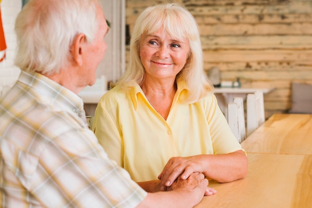 Content elderly couple sitting in cafe and holding hands