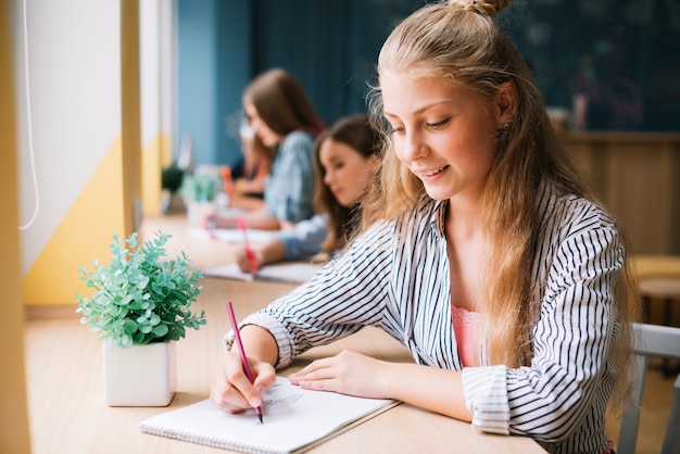 Ragazza di contenuto che prende le note nel blocchetto per appunti