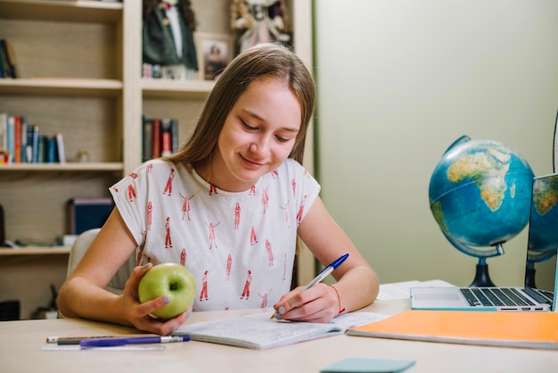 Free photo content girl with snack doing homework