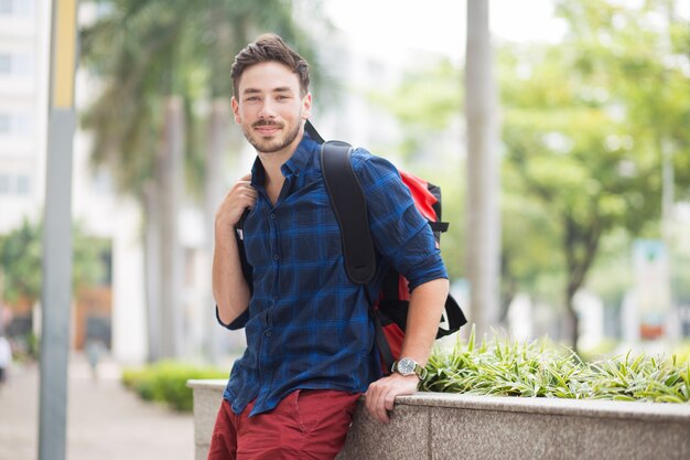 Content Handsome Traveler Sitting on Flowerbed