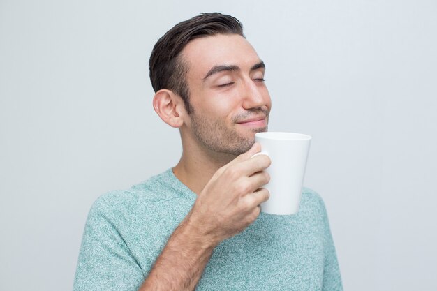 Content Handsome Young Man Smelling Tea From Mug