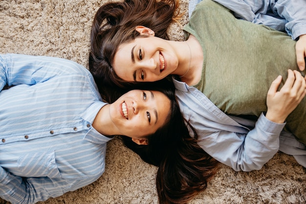 Free photo content laughing best friends lying on carpet