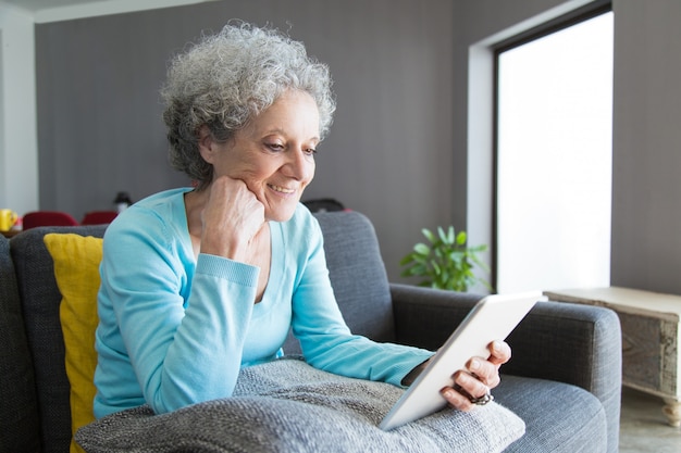 Content mature woman reading book on tablet