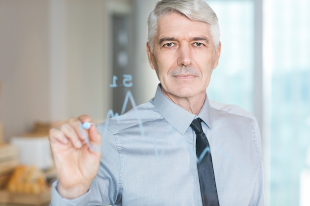 Content Senior Businessman Drawing Graph on Glass