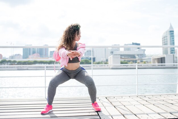 Content Sporty Woman Doing Squats on Quay