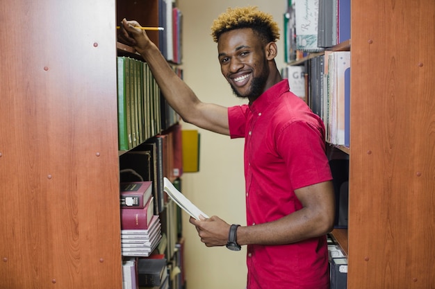 Foto gratuita studente di contenuto in posa nella biblioteca universitaria